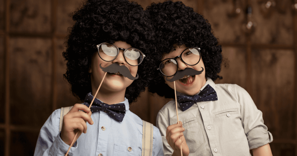 two young boys with curly wigs, bow ties and fake mustaches | how to raise gentlemen