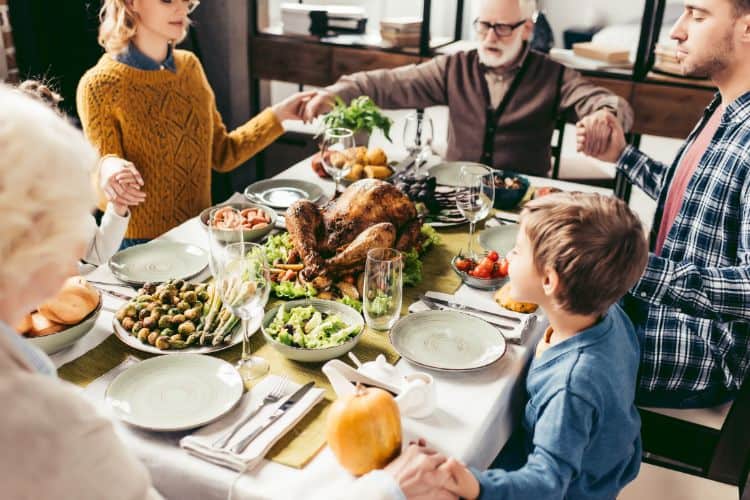 family holding hands while praying for their thanksgiving meal