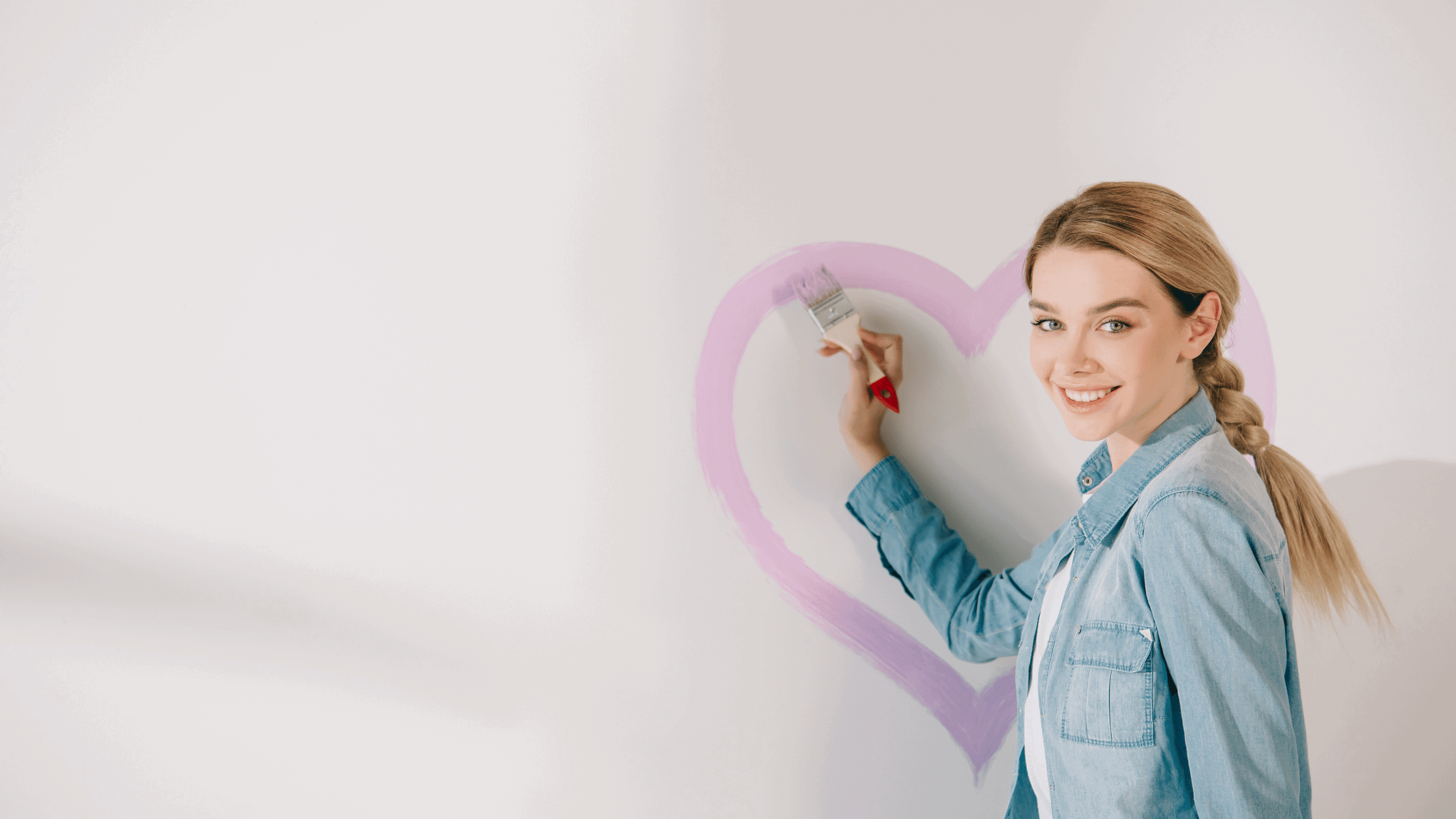 woman painting a pink heart on the wall