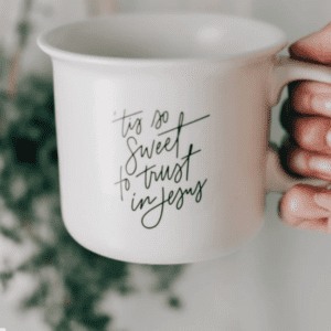 hand holding a mug that says "tis so sweet to trust in Jesus"