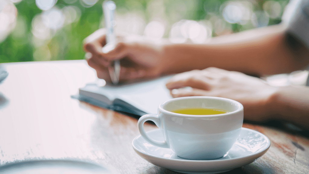 woman writing in a journal with a cup of tea nearby
