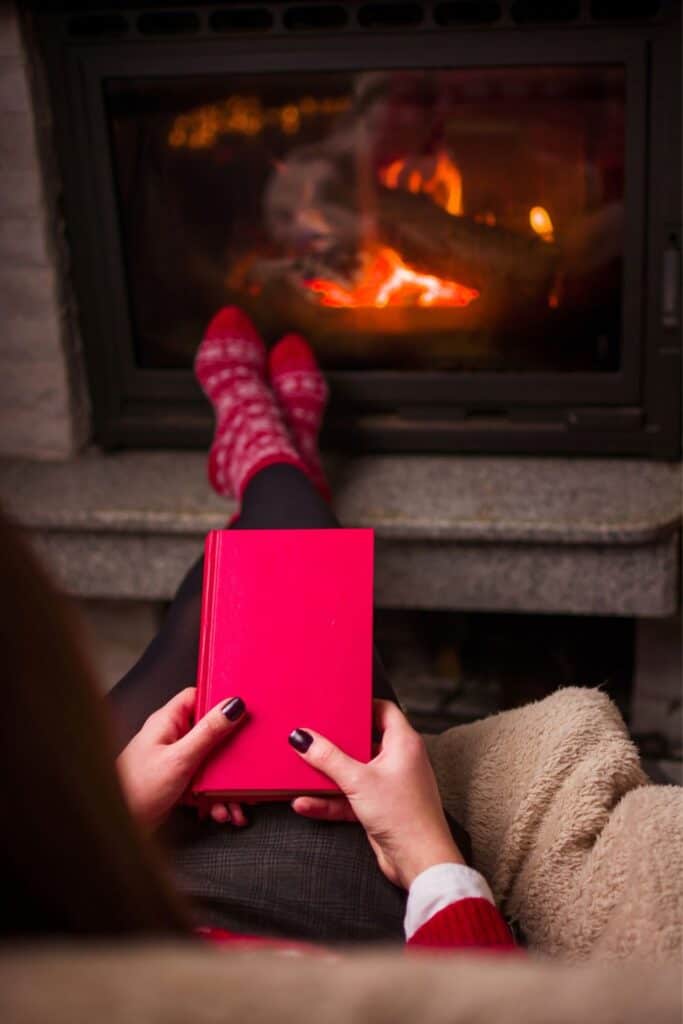 woman holding a book while sitting beside a fire