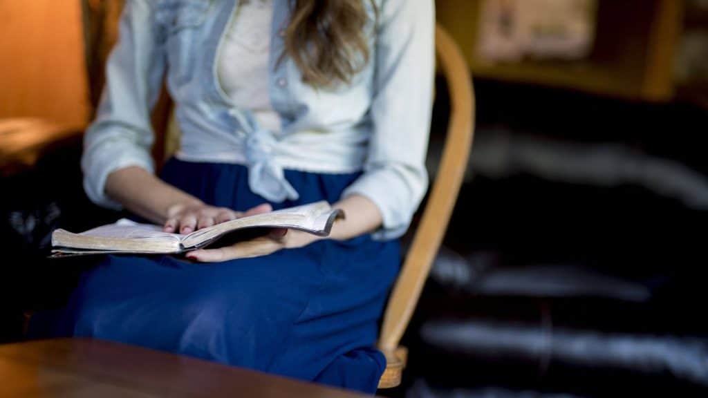 woman sitting and reading the Bible against a blurred background