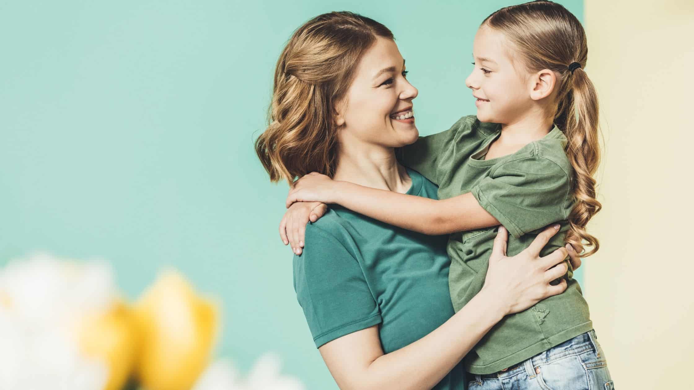 smiling mother hugging her young daughter