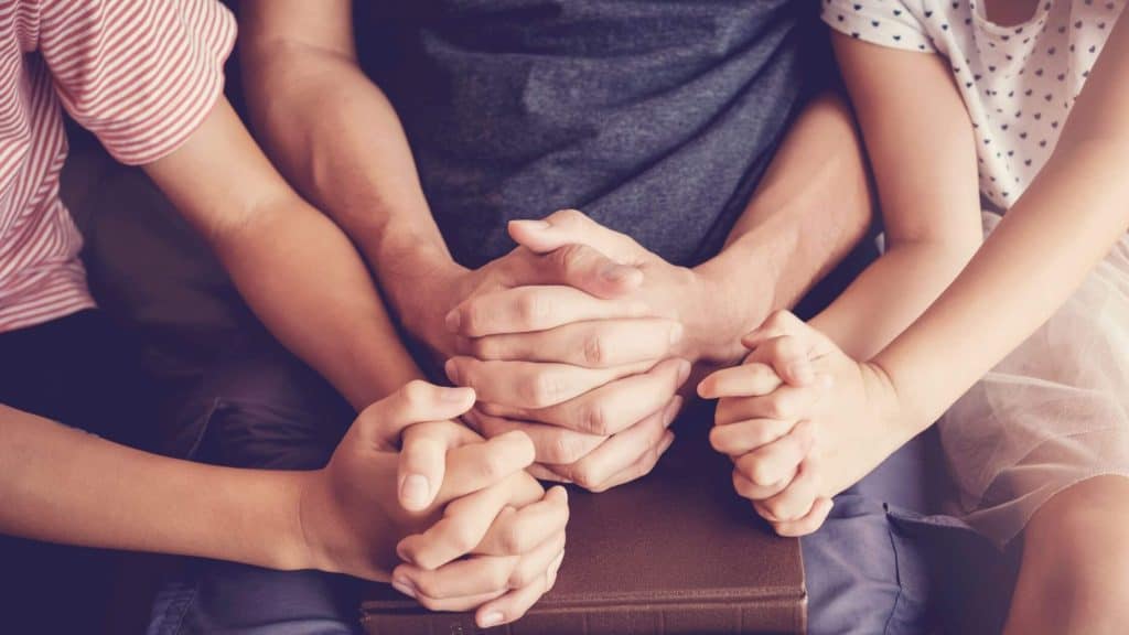view of families' hands clasped in prayer