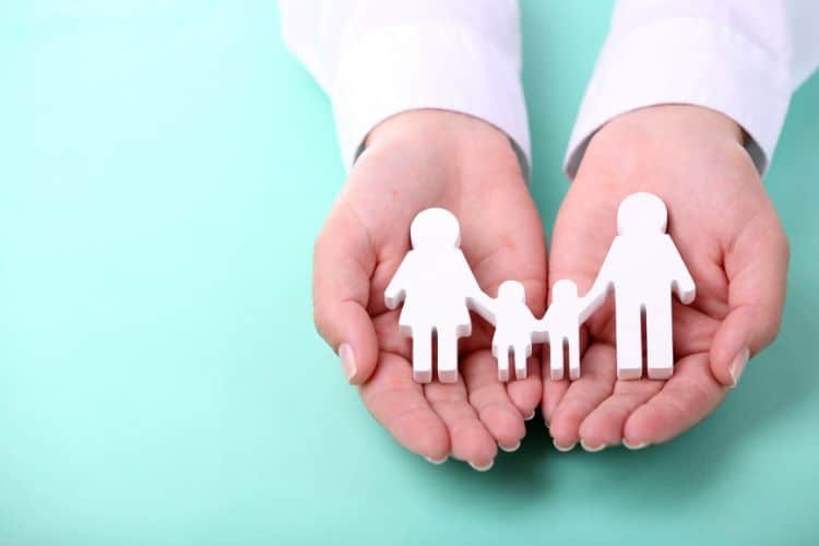 hands holding a cutout of a family