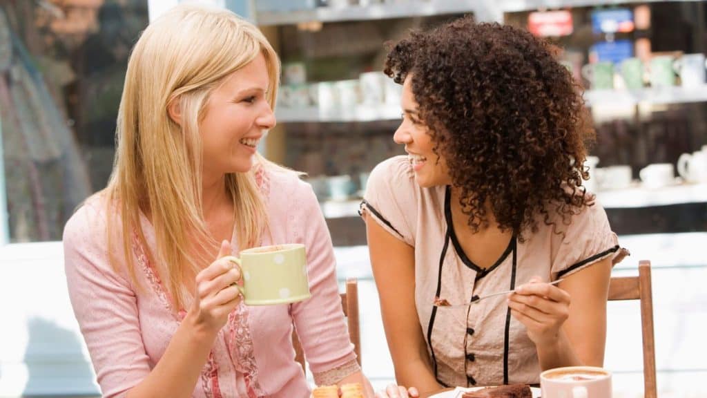 two women enjoying coffee and cake outdoors