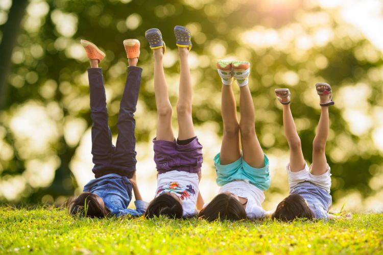 children lying in the grass with their feet in the air
