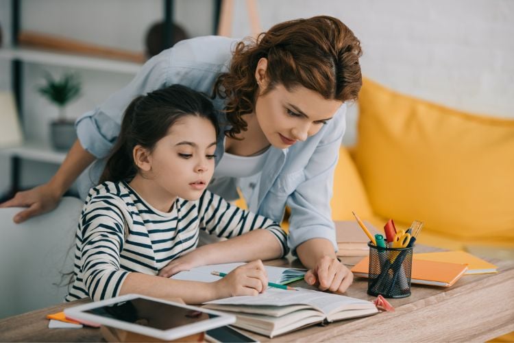 mother helping her daughter with homeschool at the table