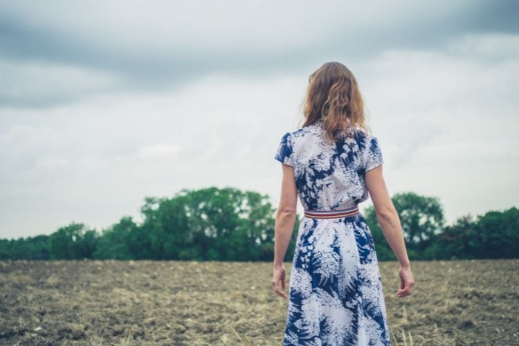 woman wearing a dress and walking in a field