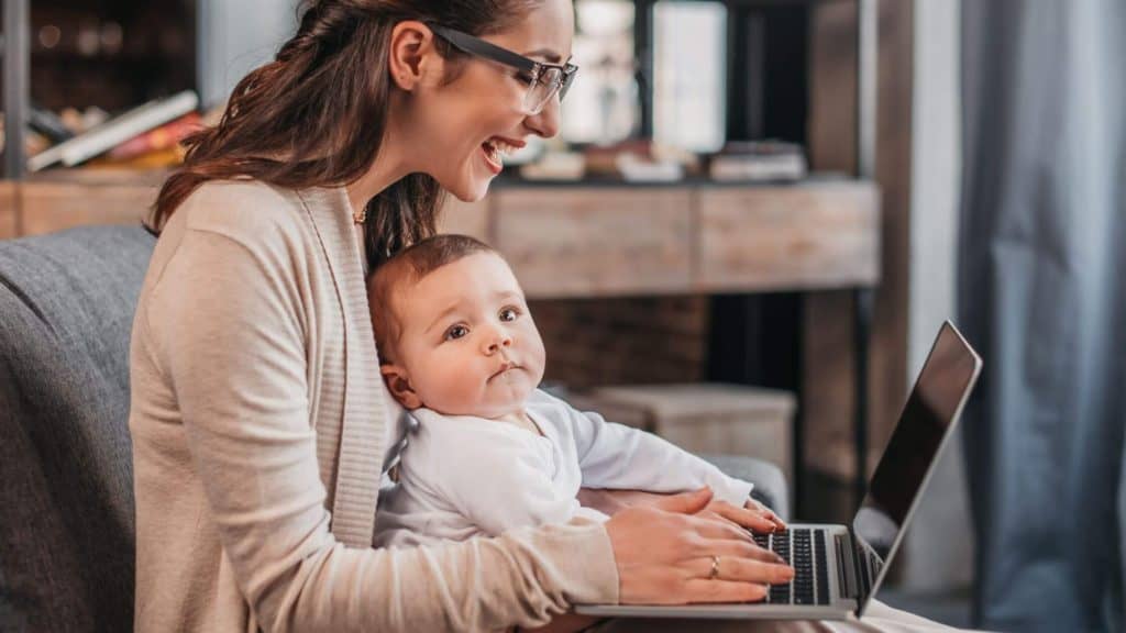 woman sitting on a couch with a laptop and a baby