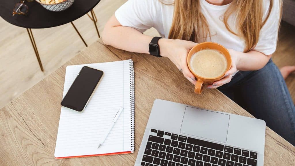 view of a desk with woman's hands holding coffee