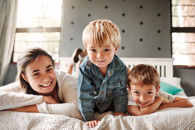 mom and two sons laying on a bed