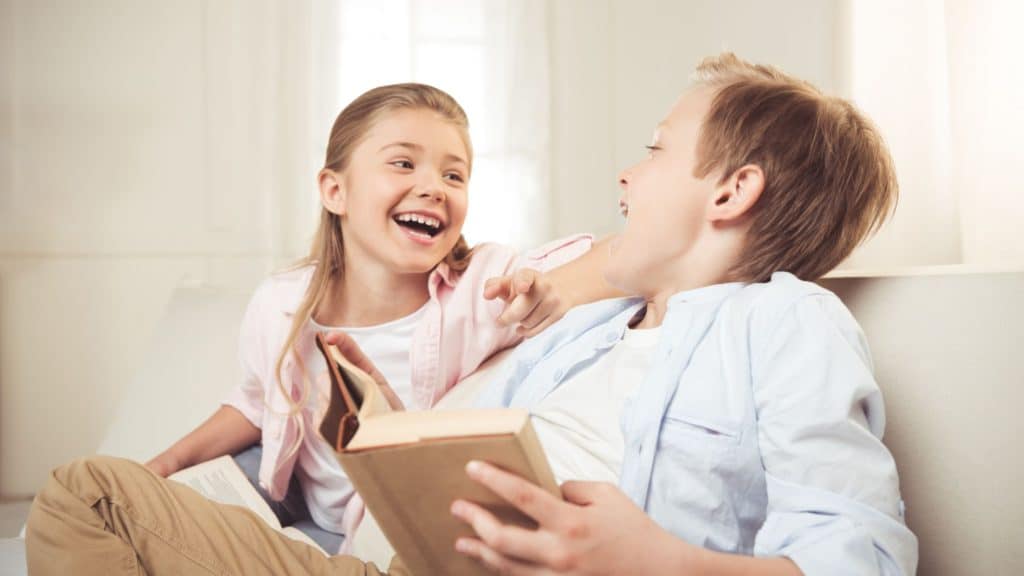 two kids laughing at a funny joke in a book