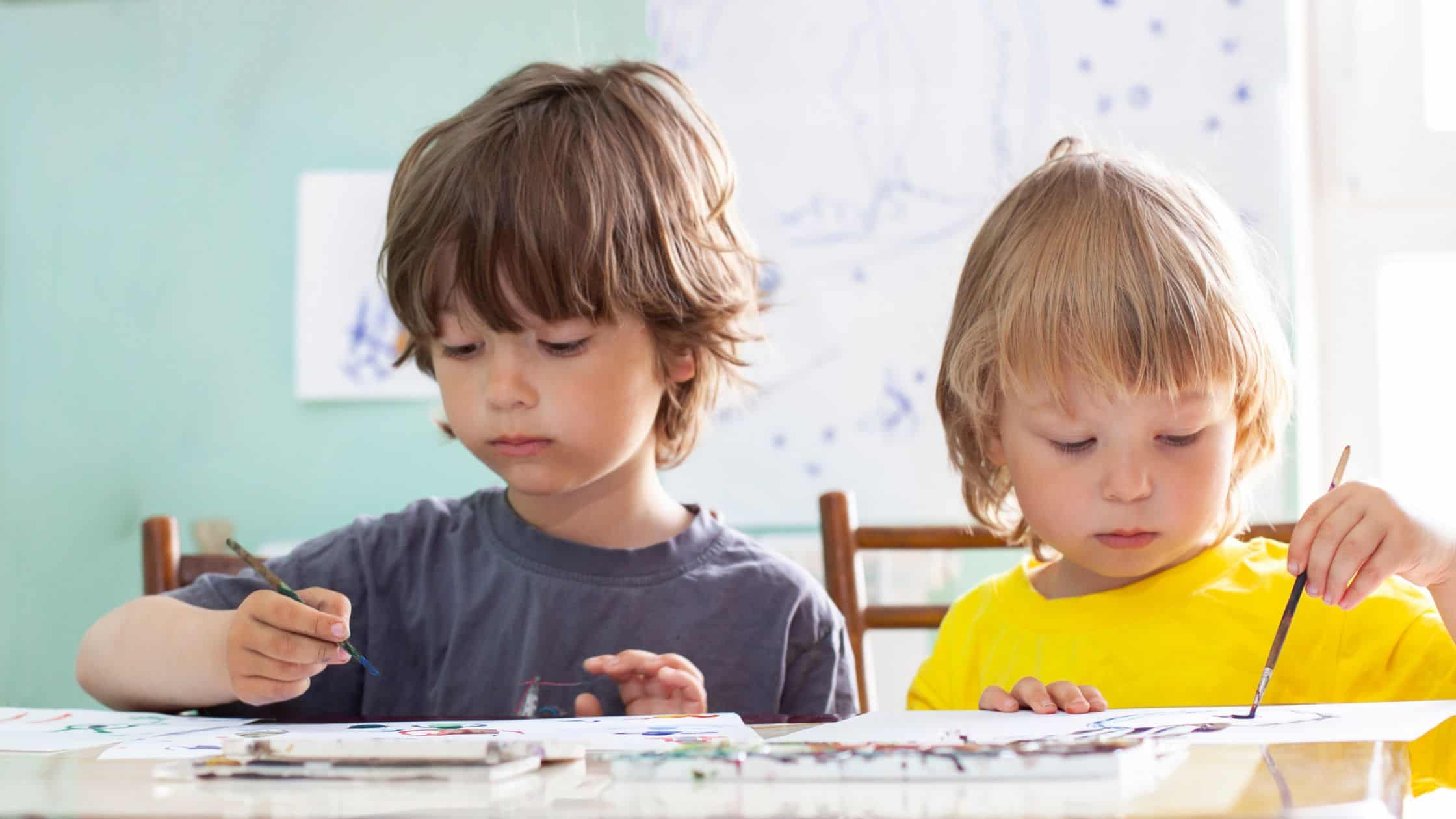 two boys painting quietly at a table