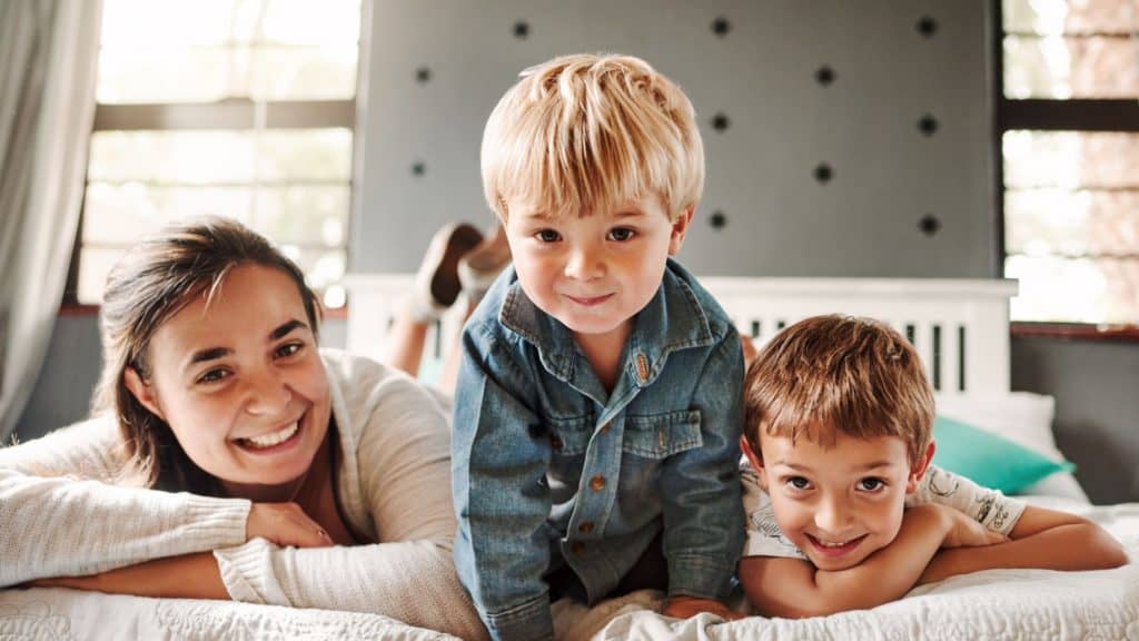 happy mom and two sons lying on a bed