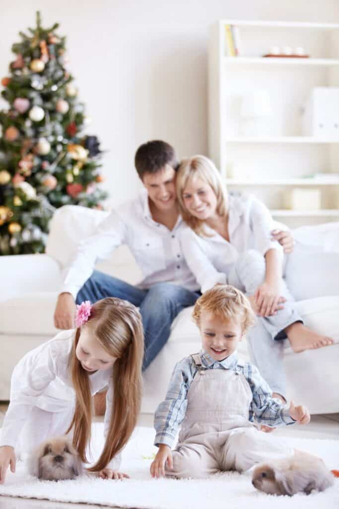 man and woman sitting on a couch with a boy and girl sitting on the floor. Christmas tree in the background