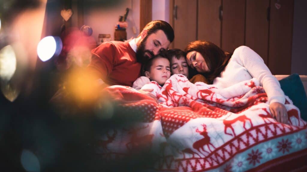 family asleep beside a Christmas tree