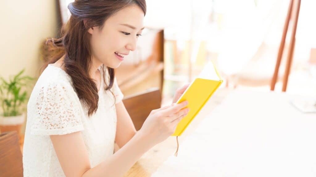 smiling woman reading a book with a yellow cover