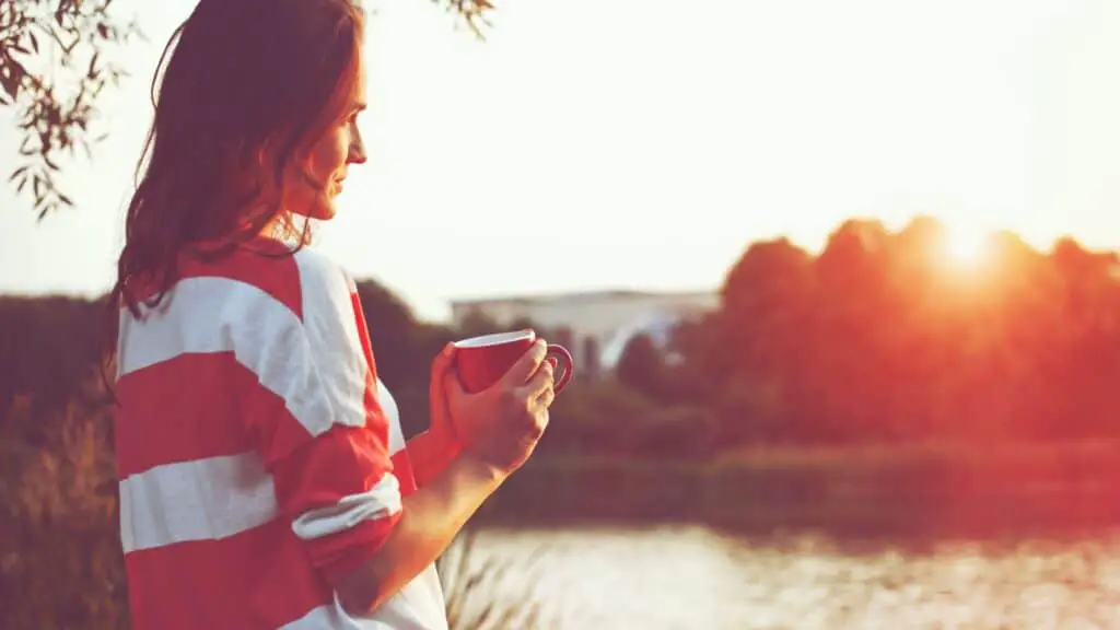 pretty young woman enjoying tea at sunrise
