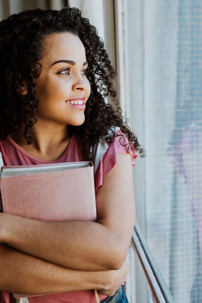 woman holding a Bible and looking out a window