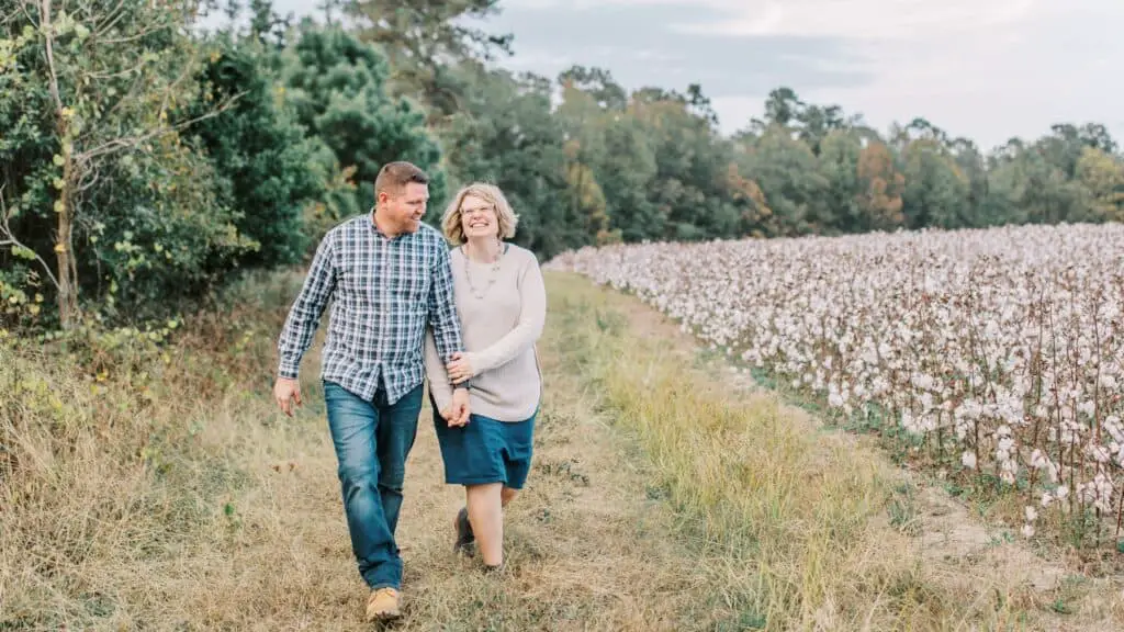 my husband and I walking through a field beside a cotton field