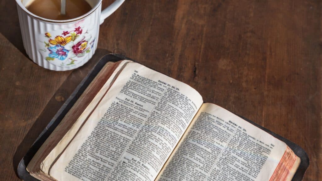 Bible open on a table with a cup of coffee