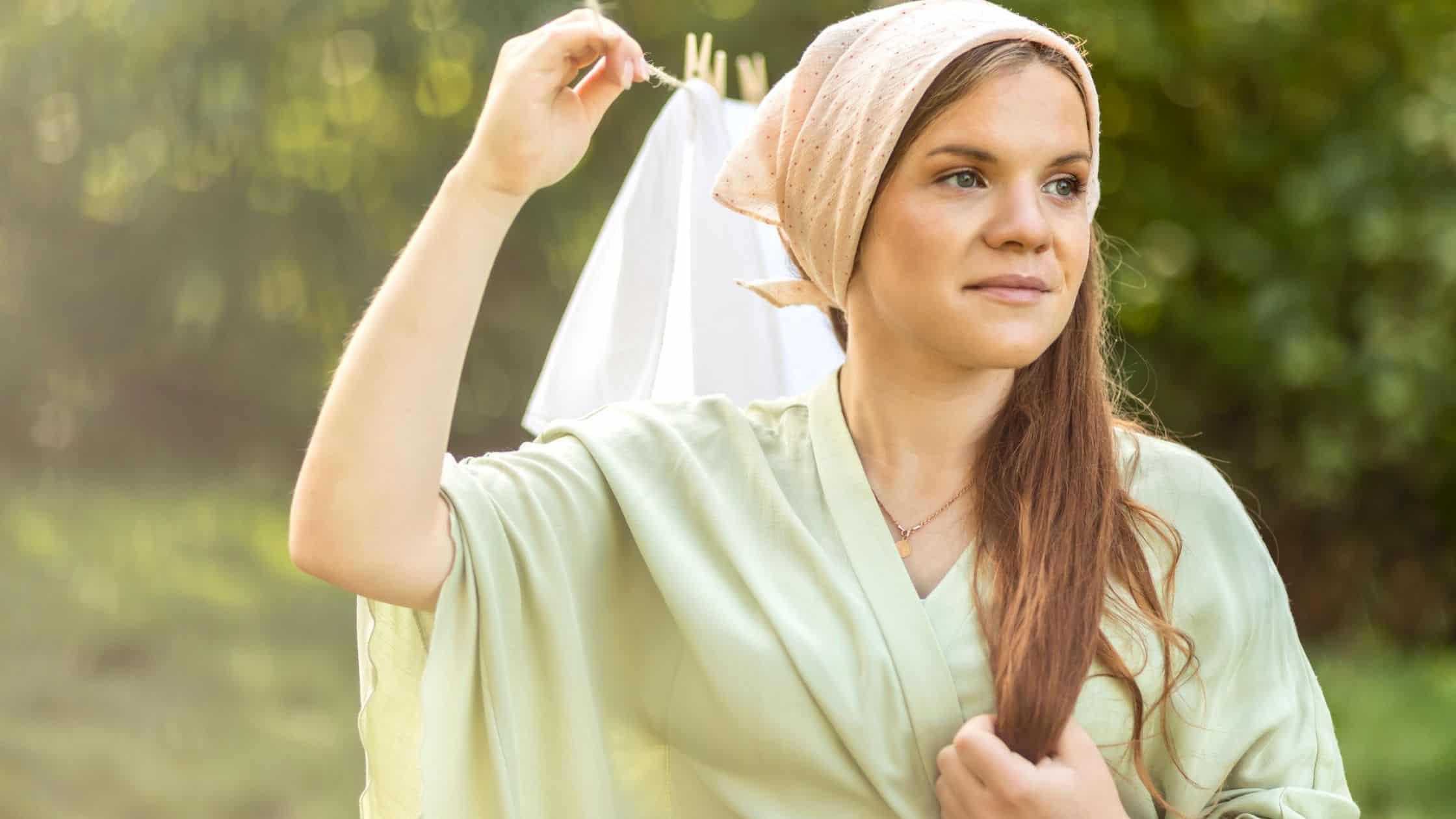 woman standing beside a clothesline wearing a head scarf