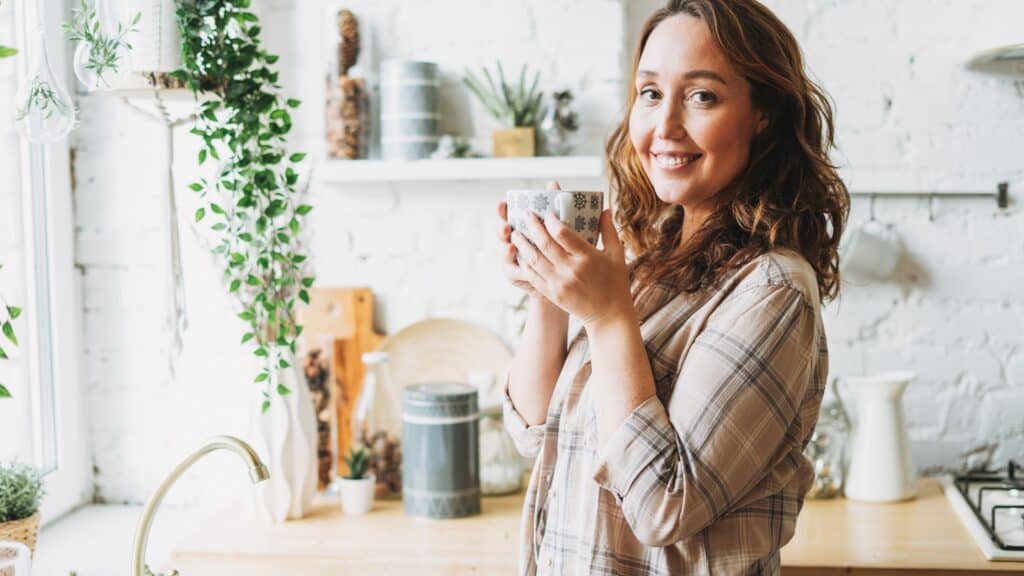 woman drinking a hot beverage in her kitchen in the morning