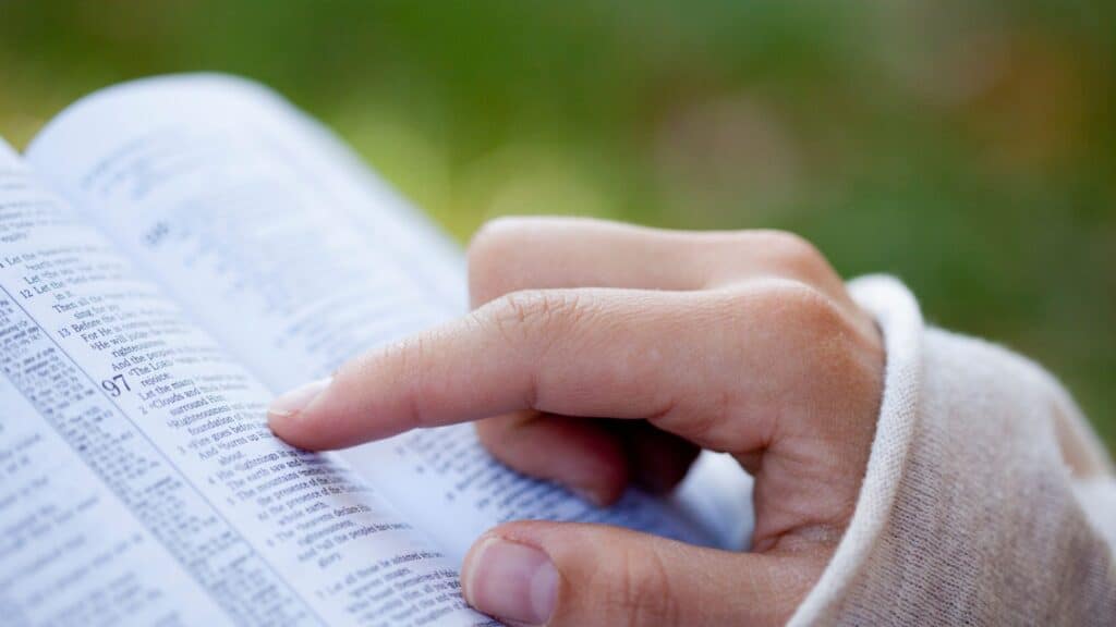 woman pointing her finger at words as she reads her Bible