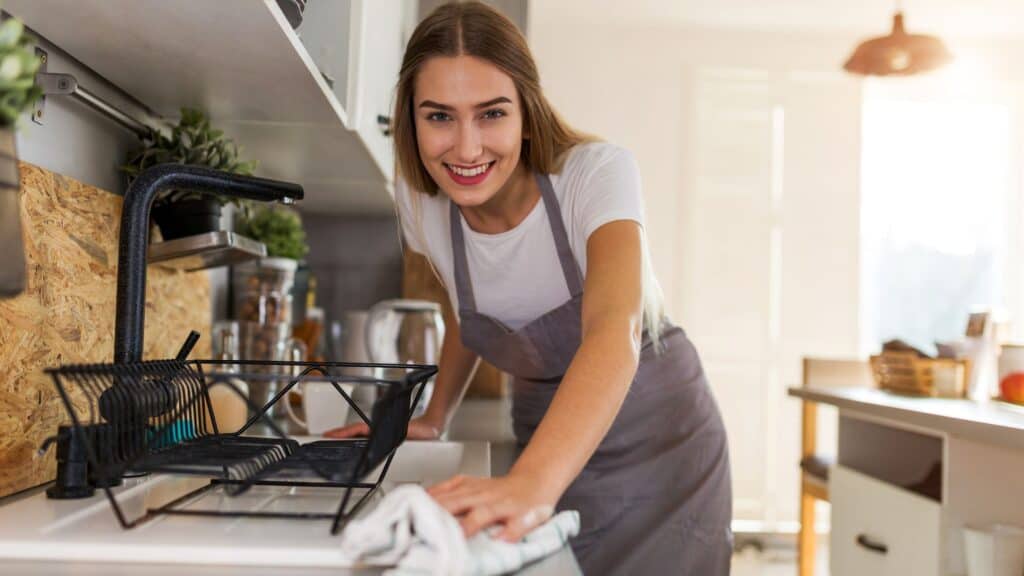 woman cleaning her kitchen while smiling