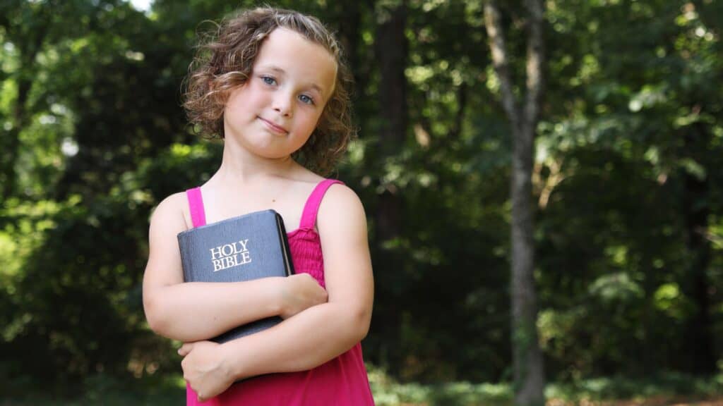 little girl with curly hair holding a Bible