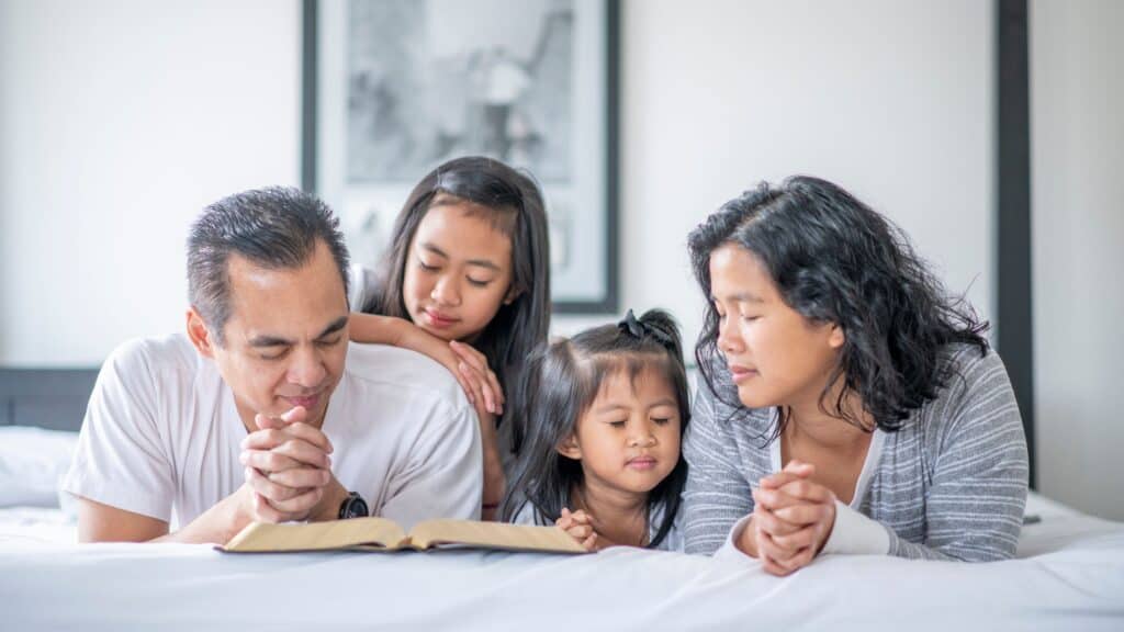 family lying on a bed reading the Bible together