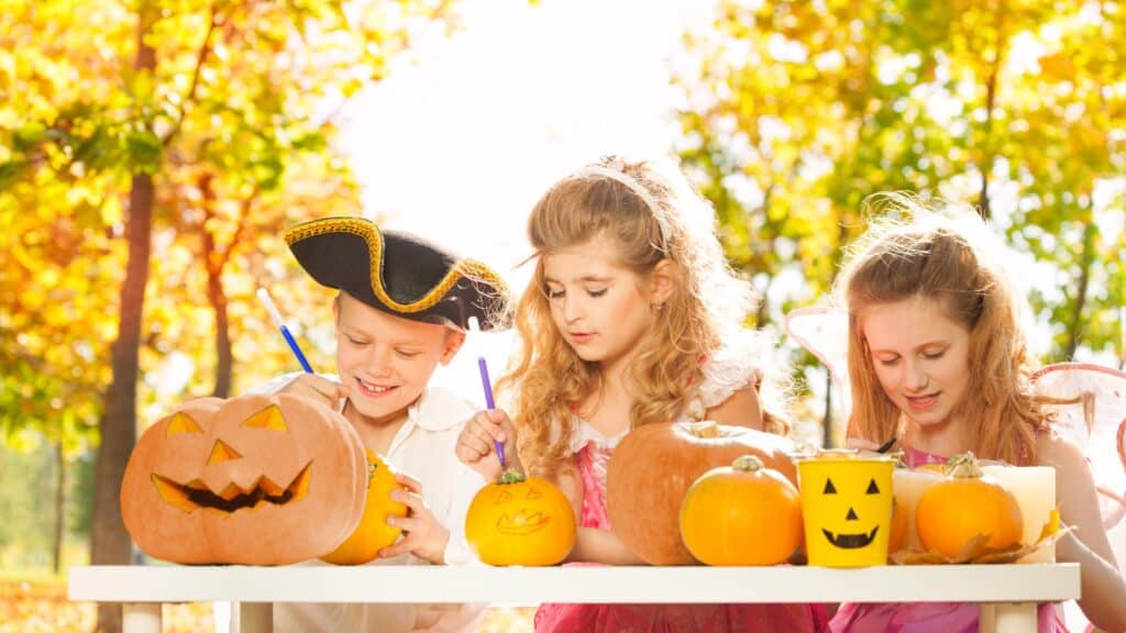 kids carving pumpkins outdoors for halloween