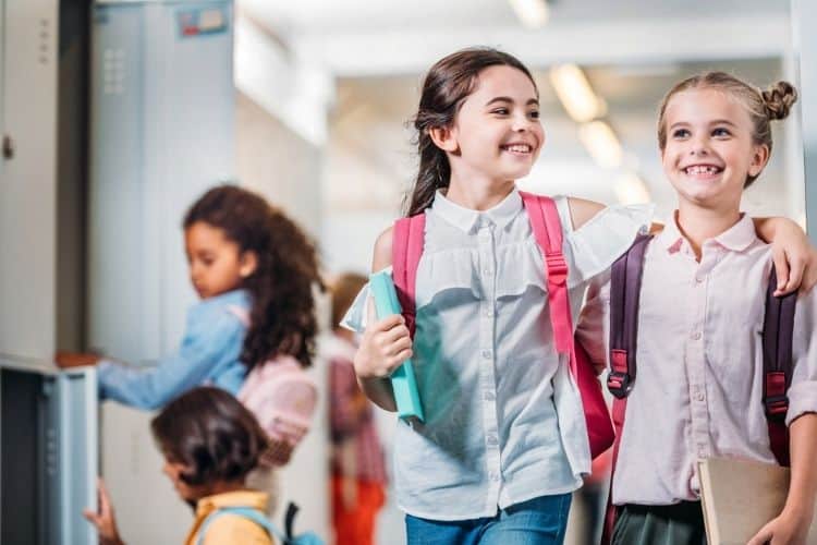 two girls walking through a school hallway