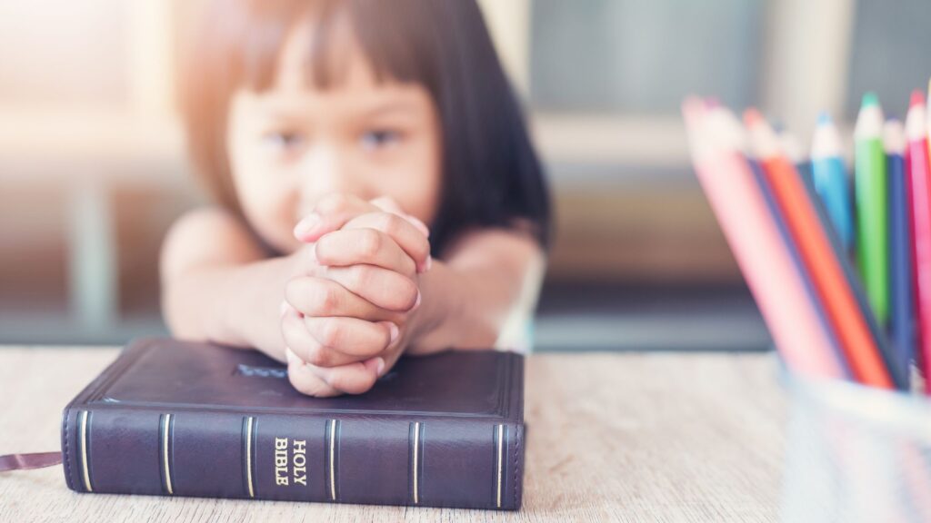 little girl in Sunday school with colored pencils and Bible