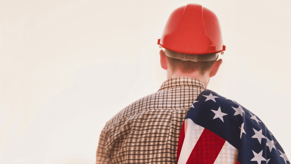 man wearing an orange hard hat and carrying an American flag over his shoulder