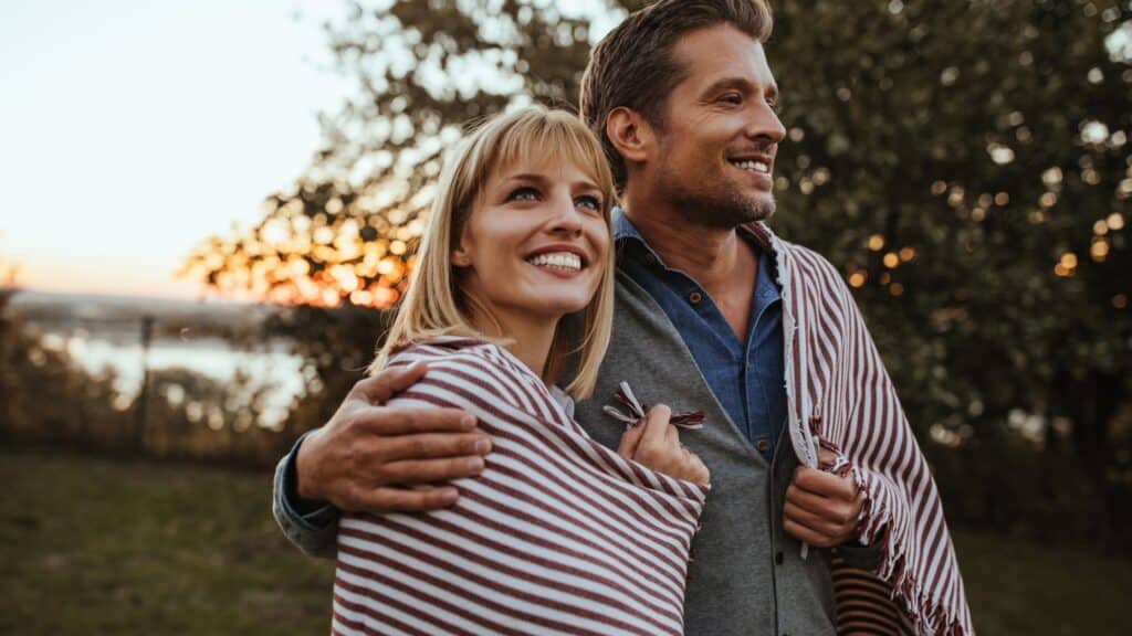 smiling man and woman outdoors with blanket wrapped around their shoulders