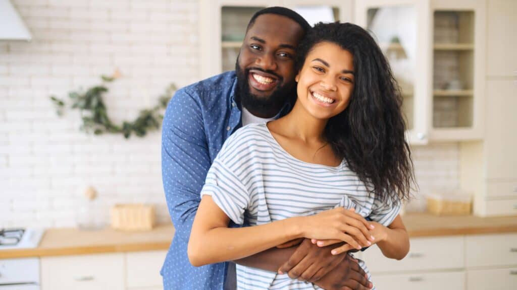 man standing behind his wife with his arms around her waist