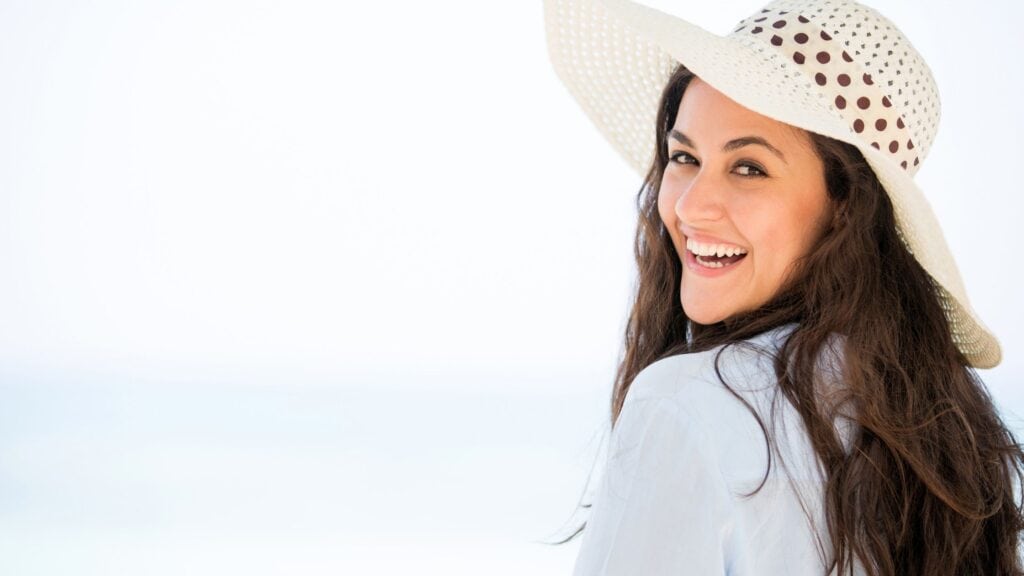 woman wearing a hat with ocean in the background