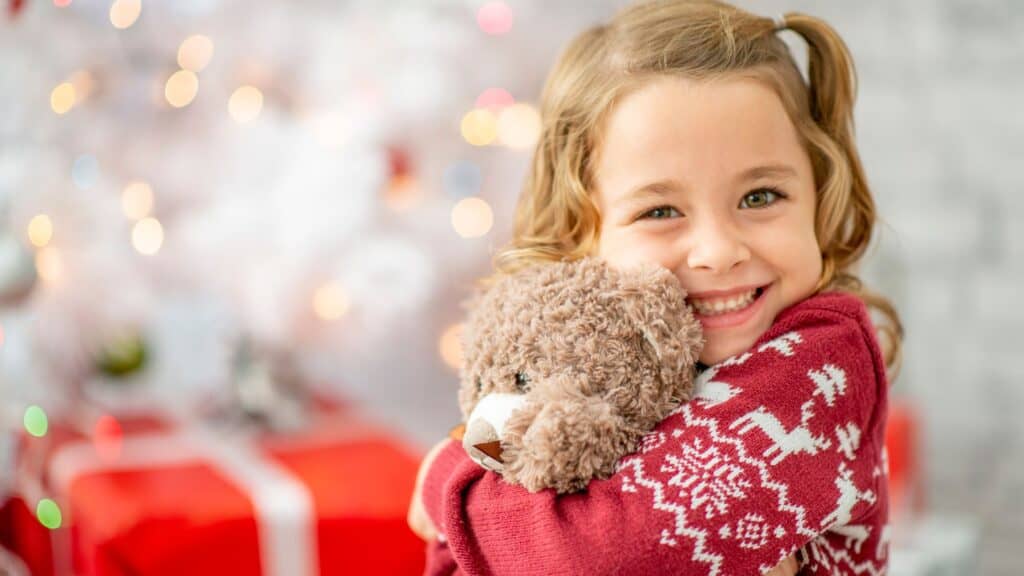 cute little girl holding a stuffed animal at Christmas time