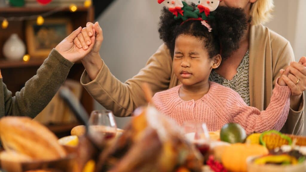 little girl sitting on her mother's lap during Thanksgiving prayer