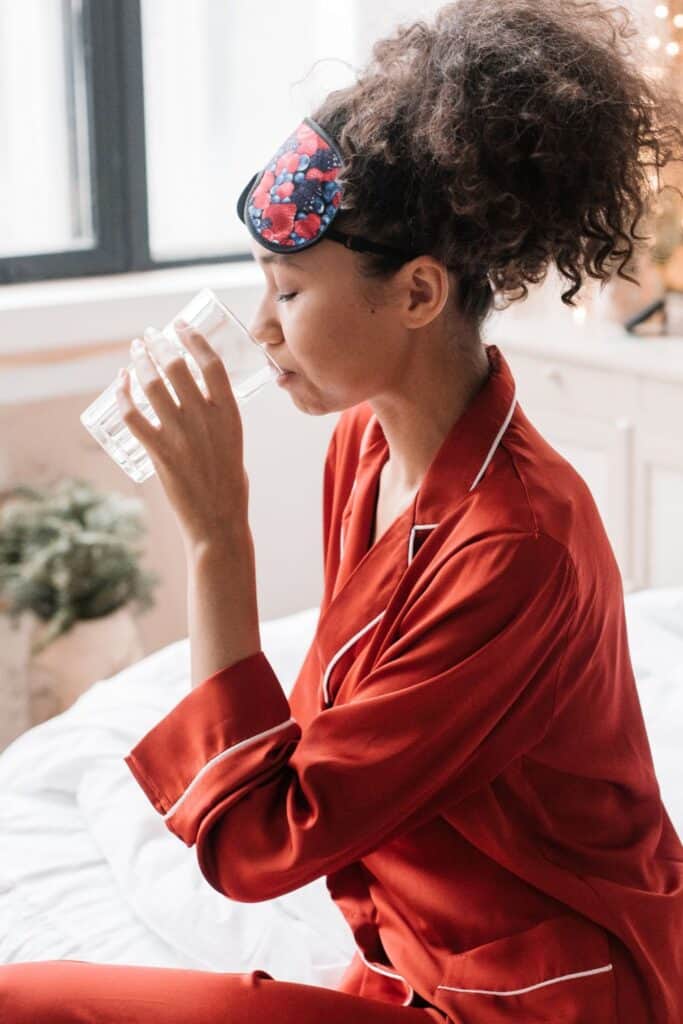 woman sitting on a bed in the morning drinking water