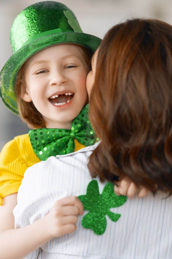 woman holding a small child wearing a green hat for st. patrick's day