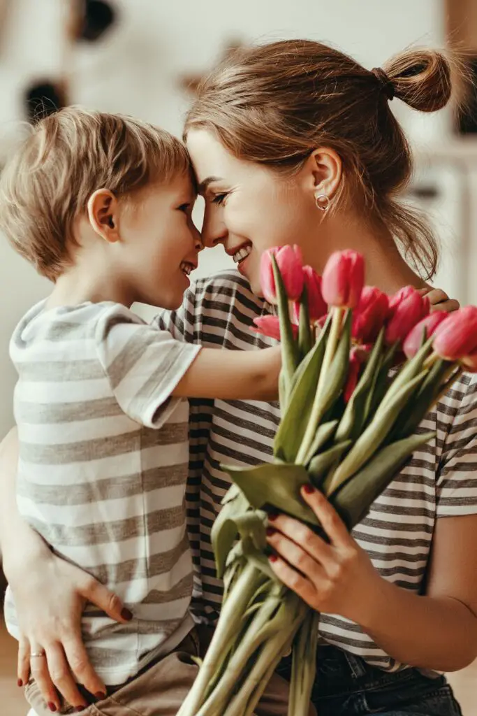 mother holding a toddler and a bouquet of flowers