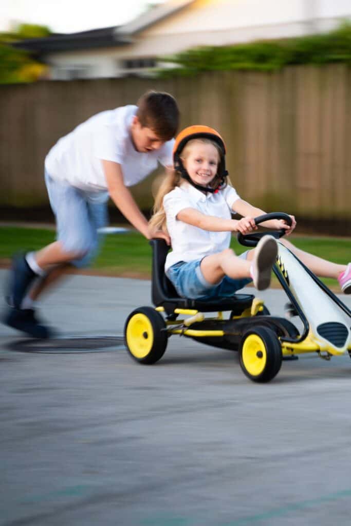 brother pushing his sister on a riding toy