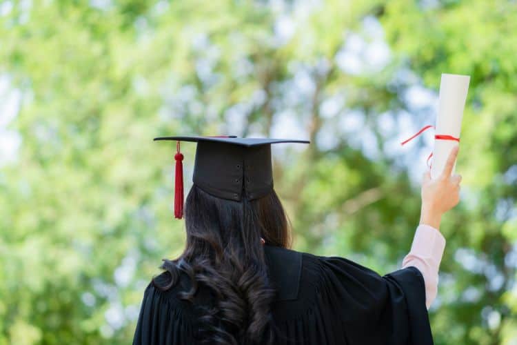 girl dressed in a cap and gown holding a diploma over her head