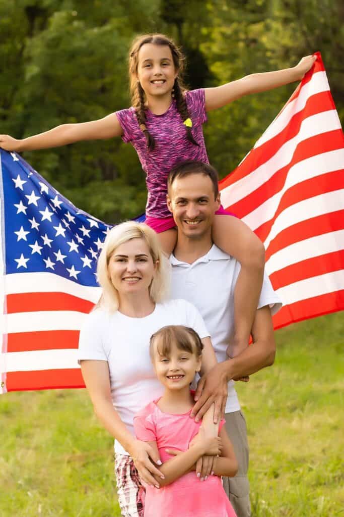 man, woman and two children holding an American flag