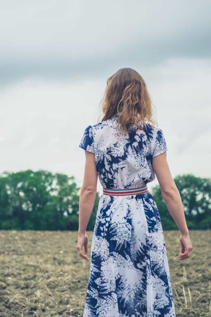 woman wearing a dress walking through a field on a cloudy day