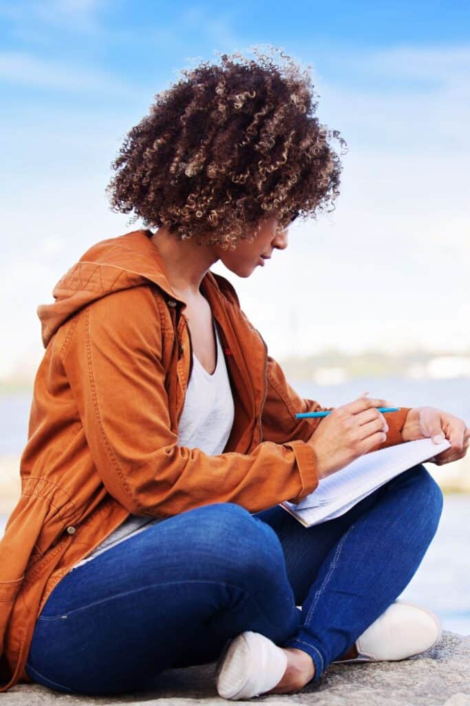 woman writing scripture on the beach